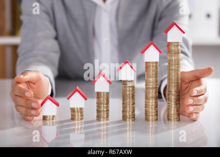 Unternehmer schützen Haus Modelle auf Gestapelte Münzen Stockfoto