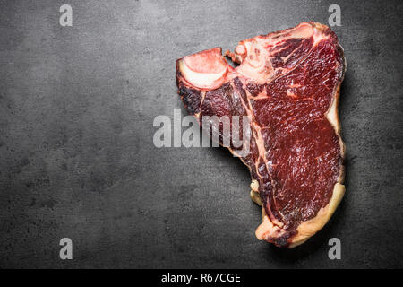 Trocken im Alter von Rindfleisch Steak T-Bone auf schwarzem Schiefer Hintergrund.