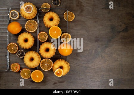 Kleine orange Bundt Kuchen mit frischen und trockenen Orangen auf Kühlung ruck, Ansicht von oben, flach, kopieren Raum Stockfoto