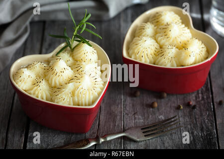 Shepherd's Pie in kleinen, individuellen Herzform rot ramikens, traditionelle britische Gerichte mit Hackfleisch und Kartoffelbrei auf rustikalen Holztisch Stockfoto