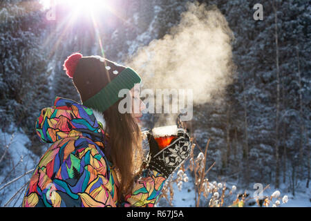 Mädchen genießt den Schnee fällt. Junge Frau in Form gestrickt ist Tee trinken im Wald bei einem Schneefall. Getönten Foto. Stockfoto