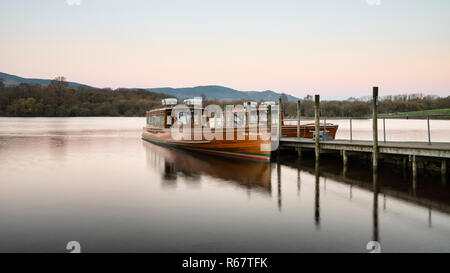 Sunrise Landschaft Blick auf Pleasure Cruise Boote in Derwentwater im Lake District, mit sanften Pastelltönen erstes Licht über die Hügel in der Ferne Stockfoto