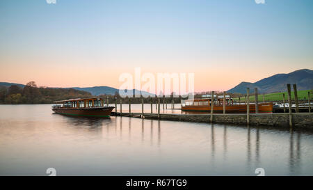 Sunrise Landschaft Blick auf Pleasure Cruise Boote in Derwentwater im Lake District, mit sanften Pastelltönen erstes Licht über die Hügel in der Ferne Stockfoto