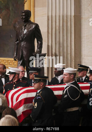 Einem US-amerikanischen militärischen Ehrengarde trägt die Schatulle des ehemaligen US-Präsidenten George H.W. Bush, vorbei an der Statue des ehemaligen Präsidenten Ronald Reagan wie es kommt in Staat in den USA Rundbau Kapitol in Washington, USA zu liegen, 3. Dezember 2018. Pool über CNP/MediaPunch Stockfoto
