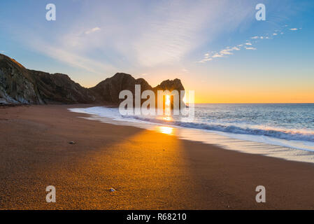 Lulworth, Dorset, Großbritannien. 4. Dezember 2018. UK Wetter: einen spektakulären Sonnenaufgang am Durdle Door auf der Dorset Jurassic Coast, als die Sonne scheint durchs Schlüsselloch der Kalkstein Bogen auf einem kalten klaren Morgen. Foto: Graham Jagd-/Alamy leben Nachrichten Stockfoto