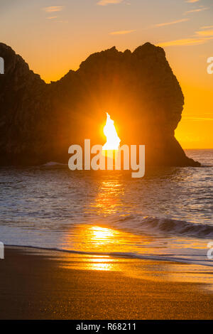 Lulworth, Dorset, Großbritannien. 4. Dezember 2018. UK Wetter: einen spektakulären Sonnenaufgang am Durdle Door auf der Dorset Jurassic Coast, als die Sonne scheint durchs Schlüsselloch der Kalkstein Bogen auf einem kalten klaren Morgen. Foto: Graham Jagd-/Alamy leben Nachrichten Stockfoto