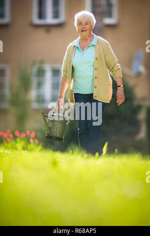 Ältere Frau tun einige Gartenarbeit in ihrem schönen Garten Stockfoto