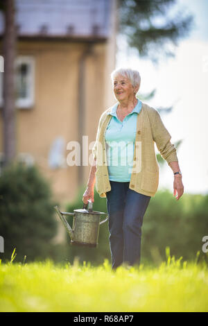 Ältere Frau tun einige Gartenarbeit in ihrem schönen Garten Stockfoto