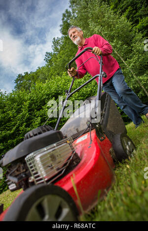 Senior woman Mähen des Rasens in seinem Garten Stockfoto