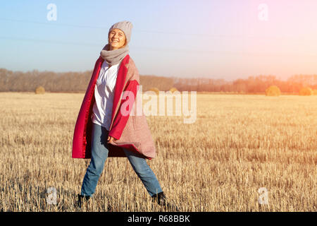 Herbst junge Frau Porträt. Schönheit freudige Modell Frau Rosa in Hut und Mantel posing und Lachen, Spaß haben im Feld. Schöne junge Frau lachend Stockfoto