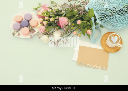 Platte von makronen auf hölzernen Tisch Kaffee, emprty Hinweis und Blumen Stockfoto