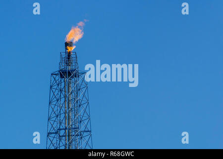 Gasfackeln in Erdölraffinerie mit blauem Himmel Hintergrund Stockfoto