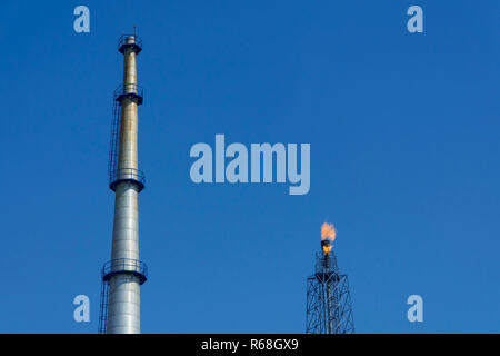 Gasfackeln in Erdölraffinerie mit blauem Himmel Hintergrund Stockfoto