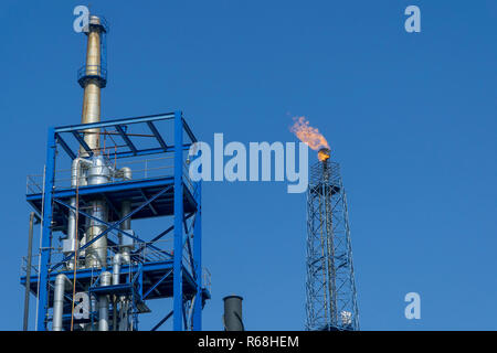 Gasfackeln in Erdölraffinerie mit blauem Himmel Hintergrund Stockfoto