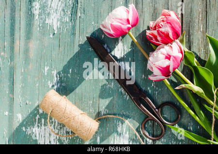 Tulpen, Schere und Garn auf einem Holzbrett. Stockfoto