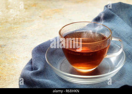 Frisch gebrühter schwarzer Tee in einem Glas Schale, dampfend heißen Getränk auf einer blau serviette, Kopieren, ausgewählte konzentrieren Stockfoto