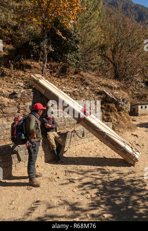 Nepal, Lukla, Lomdza, Porter mit 100 kg Holz ruht neben Pfad zu Phakding Stockfoto