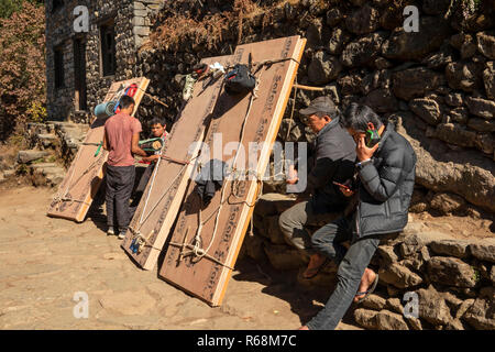 Nepal, Lukla, Lomdza, Torhüter Tragen von Lasten aus Sperrholz ruht neben Pfad Stockfoto