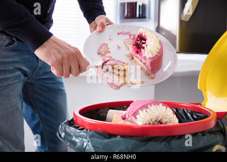 Person werfen Kuchen In Papierkorb Stockfoto