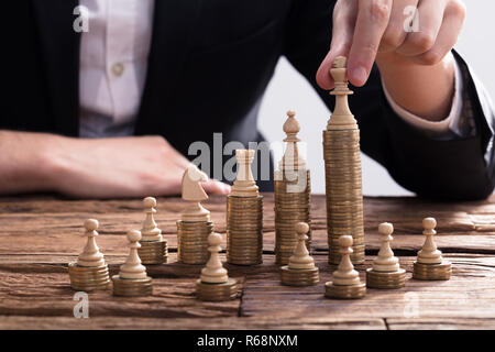 Unternehmer, die die Schachfigur auf Gestapelte Münzen Stockfoto