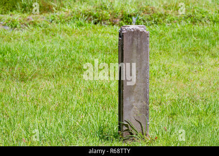 Betonpfahl auf dem grünen Rasen des Grases. Stockfoto