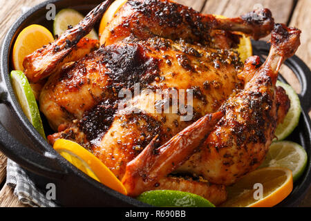 Ganze gebackene Kubanischen Hähnchen mariniert mit Mojo Sauce serviert mit Orangen und Limonen close-up in einer Pfanne. Horizontale Stockfoto