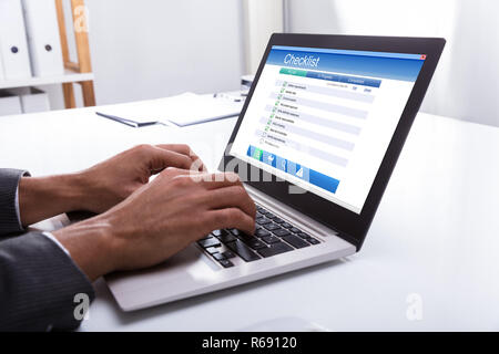 Unternehmer füllen Checkliste Formular auf Laptop Stockfoto