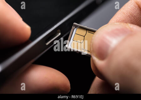 Einsetzen einer SIM-Karte in ein Handy Stockfoto