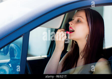 Frau nimmt Lippenstift im Auto. Stockfoto