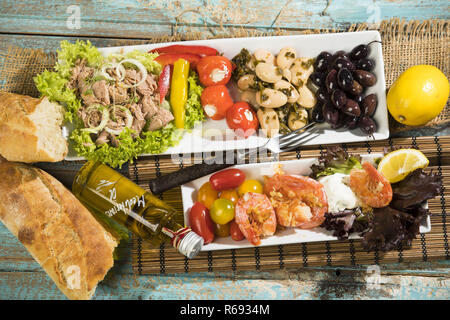 Antipasti mit Thunfisch, Salat, gefüllte Paprika, Peperoni, Bohnen, schwarze Oliven, Garnelen, saure Sahne, Tomaten und Weißbrot Stockfoto