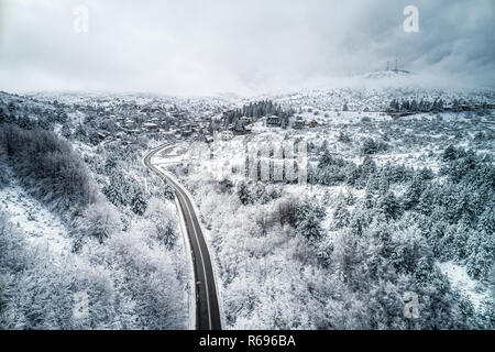 Luftaufnahme von Seli Traditionelles griechisches Dorf fallenden Schnee. Berge und die Straße während im Winter. Top Reiseziel in Nordgriechenland Stockfoto