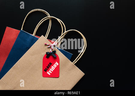 Schwarzer Freitag Verkauf von Text auf einem roten Schild mit Einkaufstasche auf schwarzem Hintergrund. Online Shopping Konzept. Stockfoto