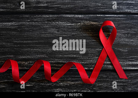 Closeup red ribbon Bewußtsein auf schwarzen Holztisch Hintergrund für den Welt-AIDS-Tag Kampagne. Stockfoto
