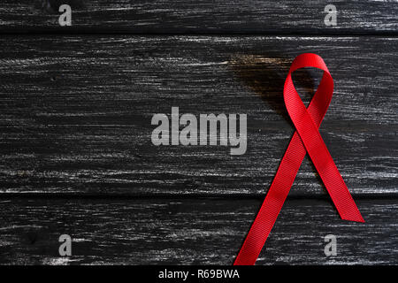 Closeup red ribbon Bewußtsein auf schwarzen Holztisch Hintergrund für den Welt-AIDS-Tag Kampagne. Stockfoto