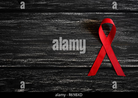 Closeup red ribbon Bewußtsein auf schwarzen Holztisch Hintergrund für den Welt-AIDS-Tag Kampagne. Stockfoto