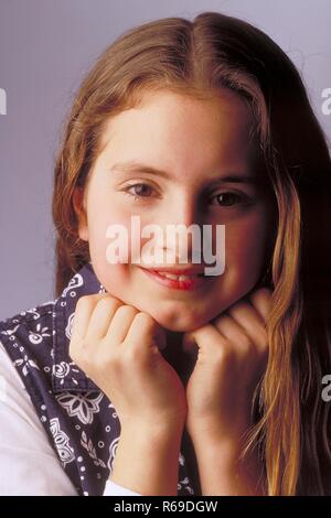 Porträt, Innenraum, laechelndes 10-jaehriges Maedchen mit langen braunen Haaren und braunen Augen bekleidet, mit blau-weisser Bluse Stockfoto