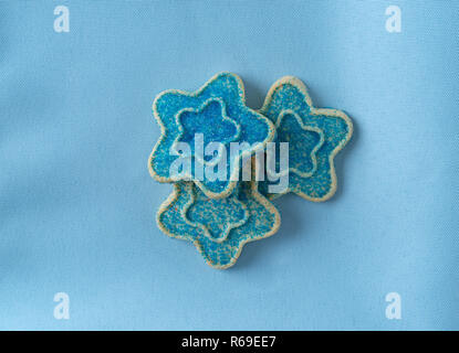 Blick von oben auf die drei sternförmigen Sugar Cookies mit blauen Streuseln auf einem Tuch Serviette. Stockfoto