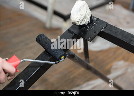 Handwerker Farben Metall mit einer Farbrolle Schwarz Stockfoto