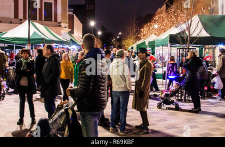 Nacht geschossen von Menschen flanieren durch ein Markt im Freien mit Weihnachtsbeleuchtung illuminiert, Navigator Square, Torbogen, London, UK Stockfoto