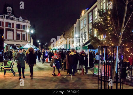 Nacht geschossen von Menschen flanieren durch ein Markt im Freien mit Weihnachtsbeleuchtung illuminiert, Navigator Square, Torbogen, London, UK Stockfoto