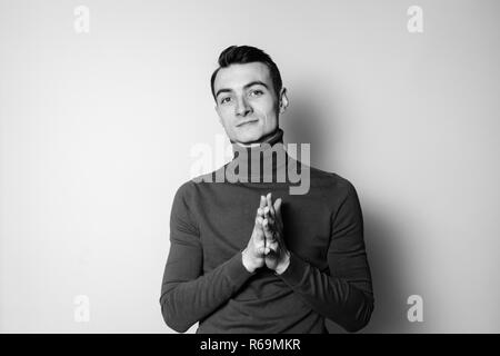 Close up Schwarz-Weiß-Porträt einer jungen Mann mit rollkragen pullover, in die Kamera schaut, gegen normales studio Hintergrund Stockfoto