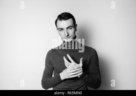 Close up Schwarz-Weiß-Porträt einer jungen Mann mit rollkragen pullover, in die Kamera schaut, gegen normales studio Hintergrund Stockfoto