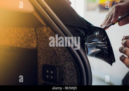 Arbeiter Hände installiert Auto Lackschutz Folie wickeln. Stockfoto