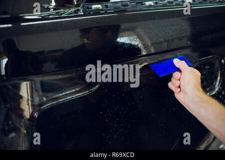 Arbeiter Hände installiert Auto Lackschutz Folie wickeln. Stockfoto