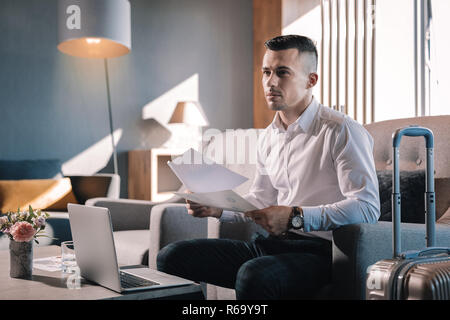 Unternehmer sitzen in der Lobby, während Geschäftsreise Stockfoto