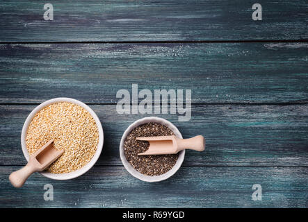 Quinoa und Chia Samen in einer Schüssel auf dem grünen Holz- Hintergrund. Beide Chia und Quinoa sind hoch in Mineralien, Antioxidantien. Stockfoto