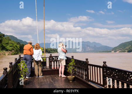 Touristen, die auf der Suche einer Landschaft an Bord eines traditionellen Holz- Bootsfahrt auf dem Fluss Mekong von Luang Prabang, Louangphabang Provinz, Laos, Asien Stockfoto