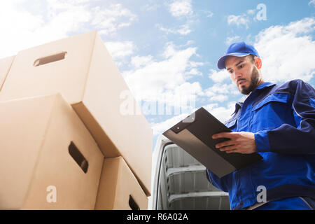 Männliche Arbeiter in der Nähe von Karton Holding Zwischenablage Stockfoto