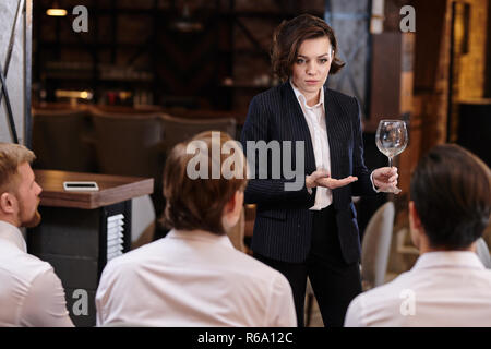 Ernsthafte zuversichtlich, attraktive junge Frau Restaurant Manager im Anzug vor Kellner und Reporting für schmutzige Weinglas Stockfoto