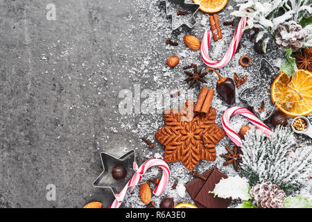 Urlaub Backen Hintergrund. Backen Weihnachten Lebkuchen cookies mit Messer und Gewürzen auf grauem Beton Tabelle mit Schnee. Urlaub Backen oder kochen in Stockfoto